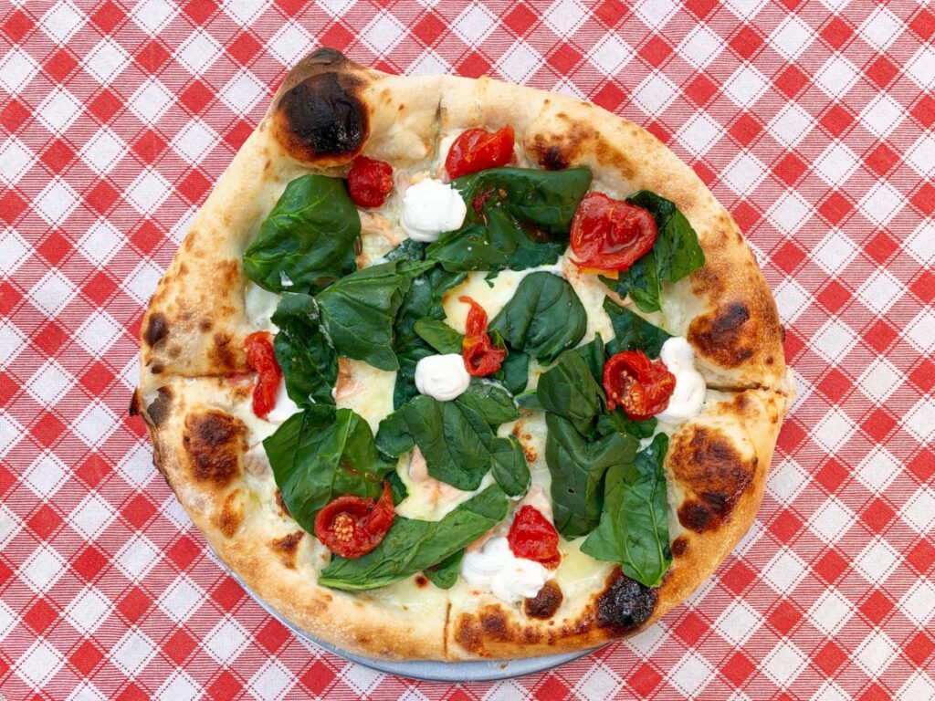 pizza con foglie verdi su piatto di ceramica bianca