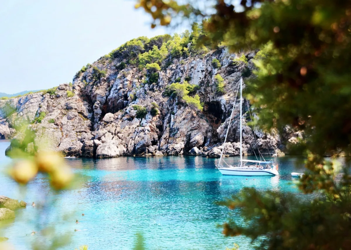 La guida definitiva di Ibiza: luoghi iconici e fughe segrete una barca a vela che galleggia nell'acqua blu di una baia